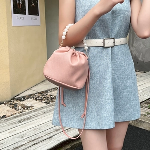 Pink lychee texture leather bucket bag with elegant pearl handle and drawstring detail