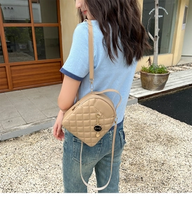 Detail eines khakifarbenen gesteppten Mini-Rucksacks mit goldenen Reißverschlüssen
