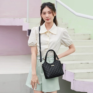 Chic black quilted tote bag with gold hardware shown on modern pastel staircase