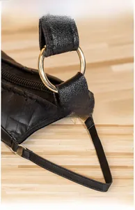 Dettagli dell'hardware dorato e texture trapuntata nera su borsa a tracolla