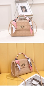 Detail of checkered embossed beige handbag featuring a silk scarf wrap and gold twist lock