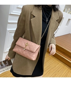 Détail d'un sac à bandoulière rose matelassé avec pendentif couronne dorée et chaîne