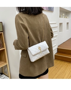 Détail d'un sac à bandoulière matelassé blanc avec boucle couronne dorée et pendentif perle
