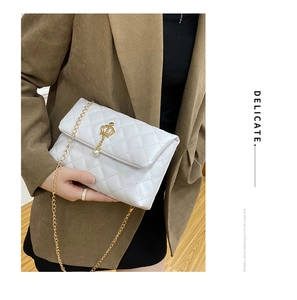 Détail d'un sac bandoulière blanc matelassé avec une couronne dorée et une perle