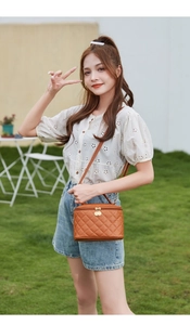 Outdoor lifestyle view of brown quilted vanity case bag with adjustable shoulder strap