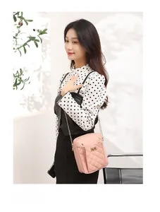 Close-up of pink quilted mini crossbody bag with gold chain strap shown on a model