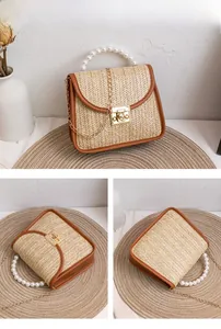 Close-up of woven straw handbag with pearl handle, gold twist lock and metal chain strap