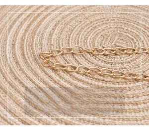 Detail showing high-quality gold metal chain strap on woven straw texture background