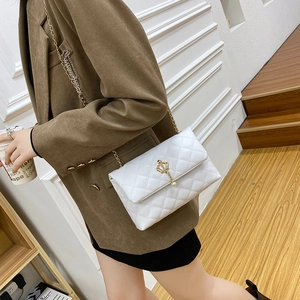 Sac bandoulière blanc matelassé avec breloque couronne dorée porté par un mannequin