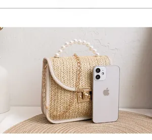 Detail of woven straw handbag featuring pearl handle and gold twist lock closure