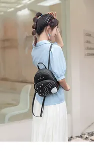 Détail d'un petit sac à dos noir avec imprimé marguerites et bretelles en cuir réglables