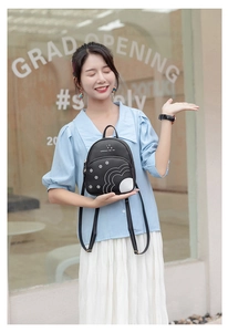 Détail d'un mini sac à dos noir avec imprimé marguerites et bretelles sur un mannequin