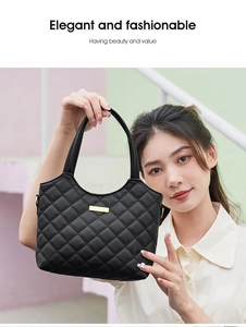 Sac fourre-tout matelassé noir avec détails dorés, porté par un mannequin