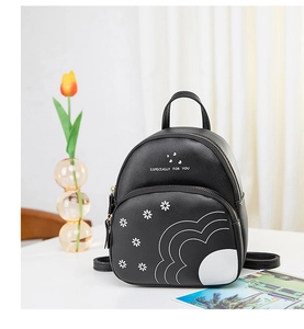 Détail d'un mini sac à dos avec imprimé marguerites sur table blanche et tulipes