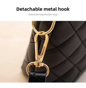 Détail du fermoir en métal doré et de la bandoulière amovible d'un sac cabas matelassé