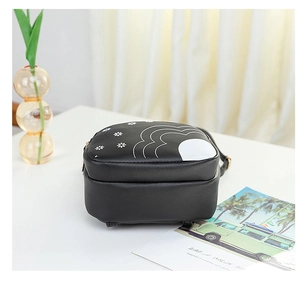 Détail du petit sac à dos en cuir noir avec imprimé floral, zip métallique et crochets