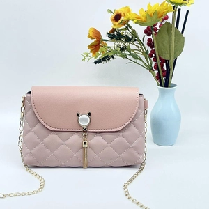 Dettaglio della borsa rosa trapuntata con nappa dorata e chiusura a gatto sui fiori