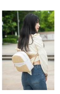 Close-up of mini woven straw and white leather backpack with zip pockets and slim straps