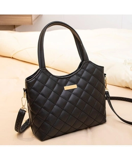 Détail du sac à main en cuir matelassé noir avec fermoir doré et bandoulière amovible