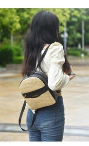 Detail of a mini woven straw and black faux leather backpack with gold metal zippers