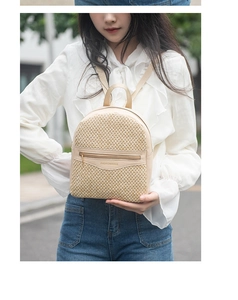 Outdoor shot of a woven mini backpack featuring beige straw material and metal zipper detail
