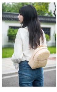 Detail of a woven straw mini backpack for women showing the dual zipper texture and styling