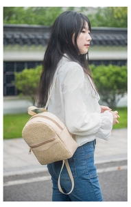 Outdoor shot of a beige woven mini backpack showing the side profile and zip pocket