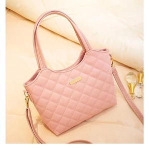 Détail du sac cabas matelassé rose avec plaque dorée et texture en cuir raffiné