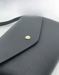 Vue rapprochée de la pochette en cuir noir texturé avec bouton-pression en métal doré