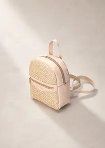 Detail of woven straw and cream leather mini backpack with golden metal zippers