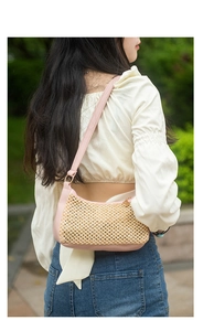 Gros plan d'un sac porté épaule tissé avec garniture en cuir rose et métal doré