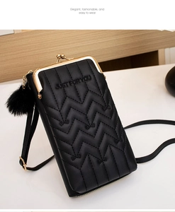 Detailed view of black quilted crossbody phone bag with gold metal clasp and plush pom pom
