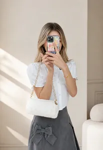 Close-up of a white quilted cylinder bag featuring a gold chain strap and elegant stitching
