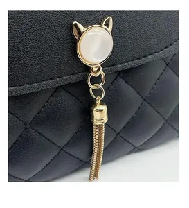 Dettaglio borsa in pelle trapuntata nera con hardware a orecchie di gatto e nappe dorate