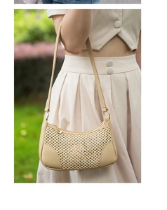 Gros plan d'un sac baguette beige tressé avec garniture en cuir et breloque dorée