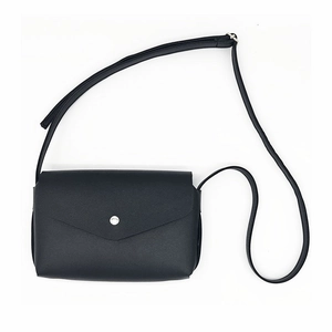 Vue détaillée d'un sac à bandoulière en cuir noir avec un fermoir rond en métal argenté