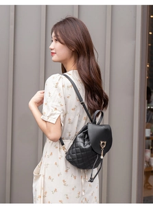 Side view of black quilted mini backpack with cat-shaped clasp on a female model