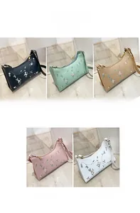 Detail shot of embroidered floral patterns on stylish crescent underarm bags in five colors