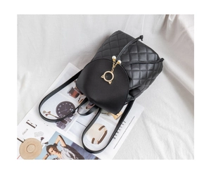Close-up of black quilted leather backpack featuring golden cat-ear metal and pearls