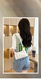 Detailed close-up of a white shoulder bag with elegant small floral embroidery and zipper