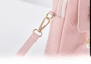 Detail of pink woven leather bag with gold hardware, zipper, and pearl charm