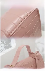 Detail of pink crocodile pattern handbag showing precision stitching and handle structure