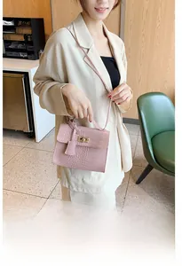 Detail of pink crocodile pattern square handbag with metallic lock and shoulder strap
