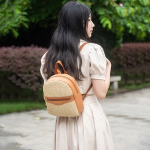 Women's woven brown mini backpack with adjustable straps shown in an outdoor setting