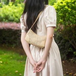 Sac hobo tissé beige avec finitions en cuir sur l'épaule d'un mannequin
