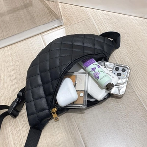 Detail showing internal storage capacity of the black quilted waist bag with gold zippers