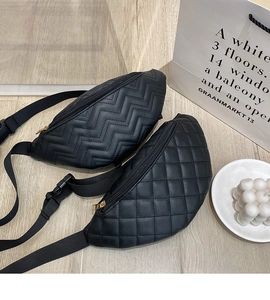Detail of two black quilted waist bags with wave and diamond patterns and gold zippers