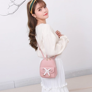 Pink mini backpack for women with a large white bow decoration and adjustable straps