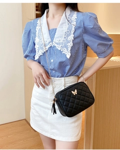 Detail of black quilted leather camera bag with gold butterfly clasp and tassel