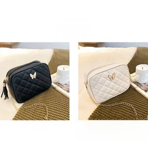 Quilted crossbody camera bag with metal butterfly detail and decorative tassel in black and white